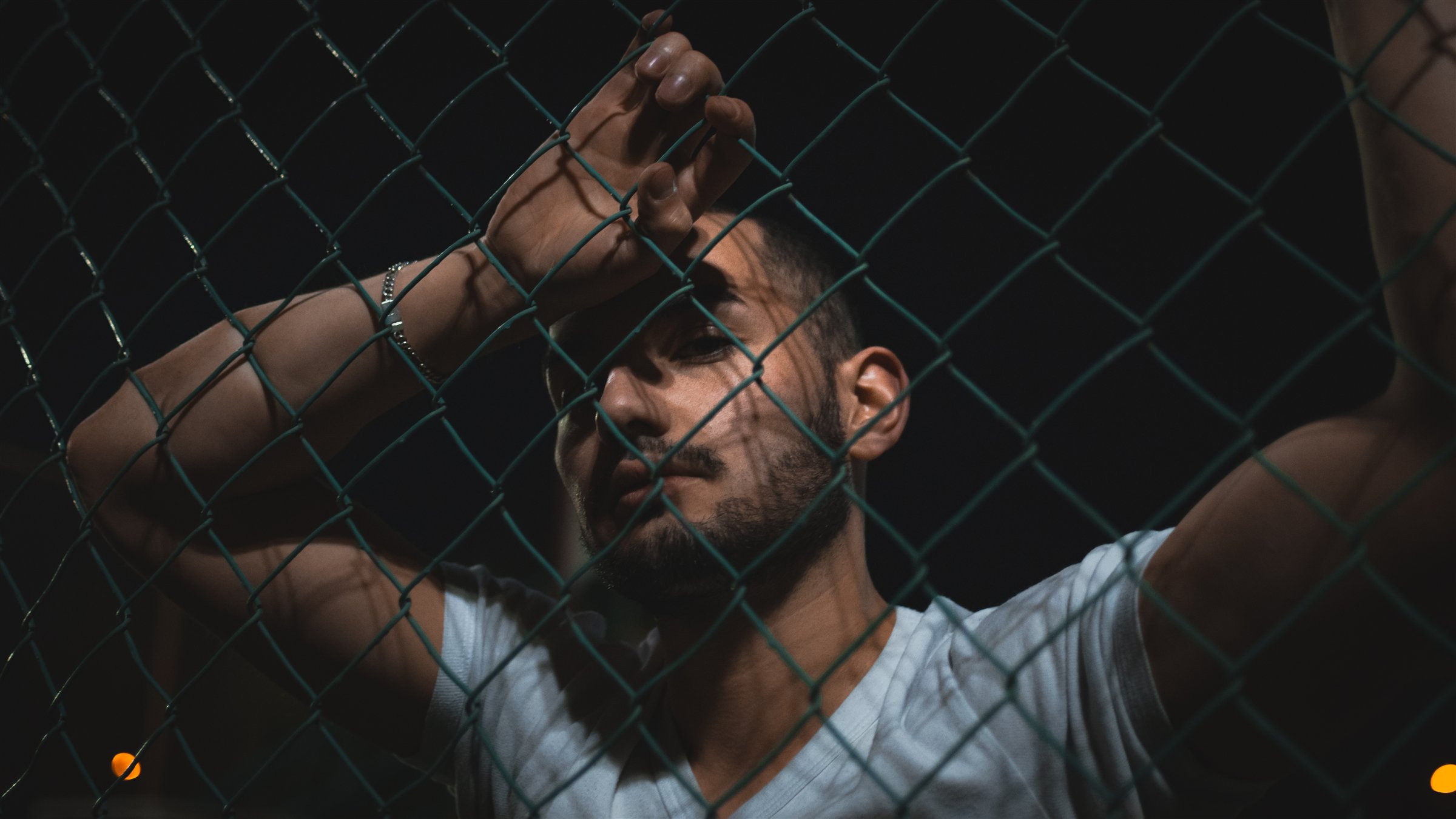 Retrato nocturno de una persona detrás de una reja metálica